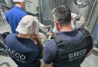 Foto de policiais da Geaco e funcionários de indústria de leite ao redor de tonel. Foto de policiais da Geaco e funcionários de indústria de leite ao redor de tonel.