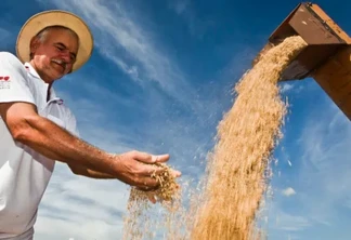 Foto de um produtor avaliando o seu milho produzido, sendo descarregado pela colheitadeira. Foto de um produtor avaliando o seu milho produzido, sendo descarregado pela colheitadeira.