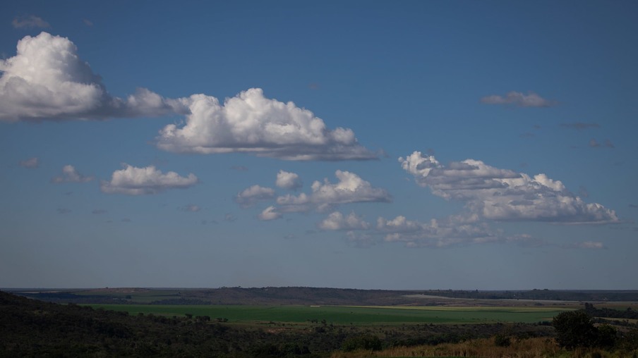 Foto de área verde sob céu azul com poucas nuvens.
