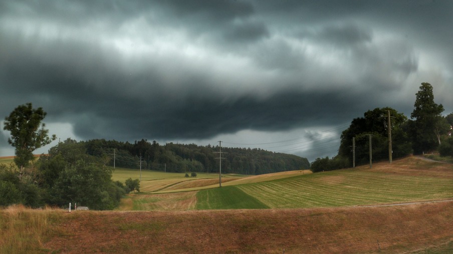 A foto mostra nuvens de chuva e terrenos cultiváveis de lavoura