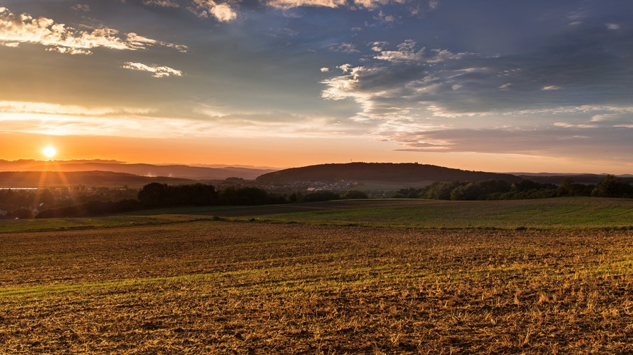 Pôr do sol sob um campo grande e plano com montanhas ao longe. Pôr do sol sob um campo grande e plano com montanhas ao longe.