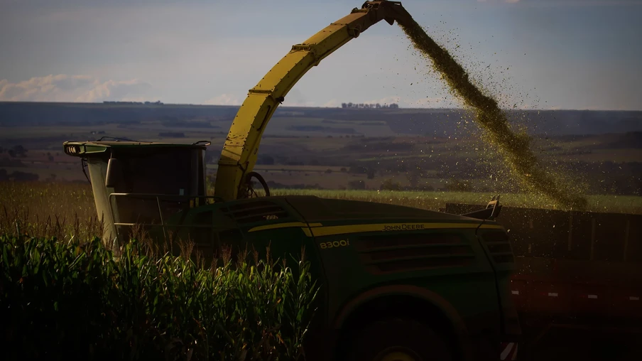 Foto de colheitadeira em lavora de milho. Ela está despejando grãos em carreta. Foto de colheitadeira em lavora de milho. Ela está despejando grãos em carreta.