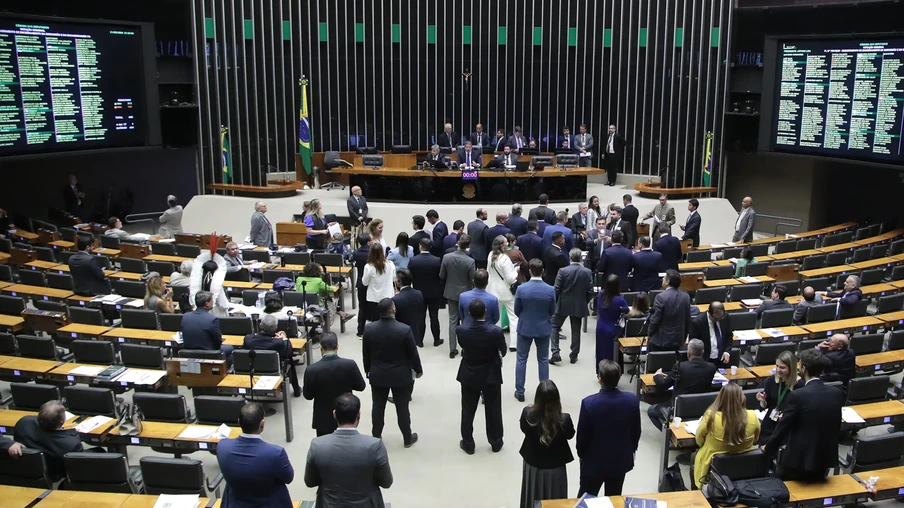 Foto de deputados no plenário da Câmara de Deputados durante Sessão Deliberativa. A maioria está em pé em frente a mesa da presidência. Foto de deputados no plenário da Câmara de Deputados durante Sessão Deliberativa. A maioria está em pé em frente a mesa da presidência.