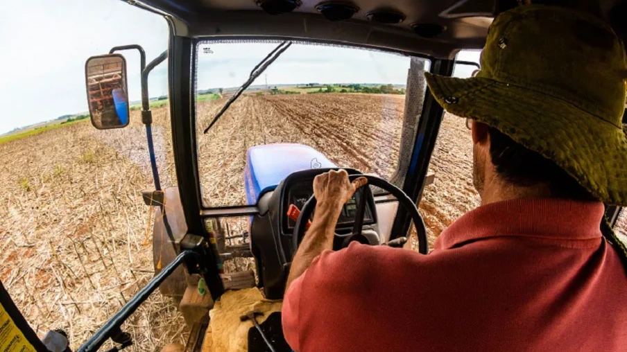 Foto de homem dentro de trator em lavoura de soja. Foto de homem dentro de trator em lavoura de soja.