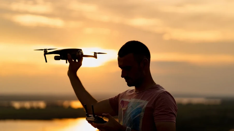Silhueta do homem pilotando um drone ao pôr do sol com céu ensolarado no fundo. Silhueta do homem pilotando um drone ao pôr do sol com céu ensolarado no fundo.