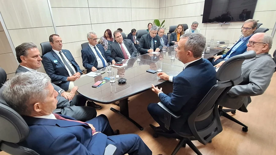 Foto de várias pessoas sentadas ao redor de mesa de reunião. Foto de várias pessoas sentadas ao redor de mesa de reunião.