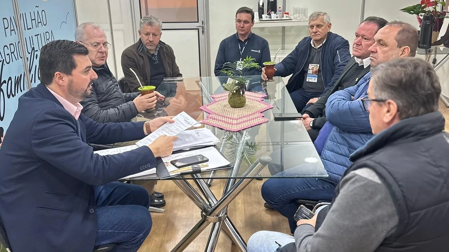Foto de homens sentados ao redor de mesa de vido enquanto conversam. Alguns seguram chimarrão. Foto de homens sentados ao redor de mesa de vido enquanto conversam. Alguns seguram chimarrão.