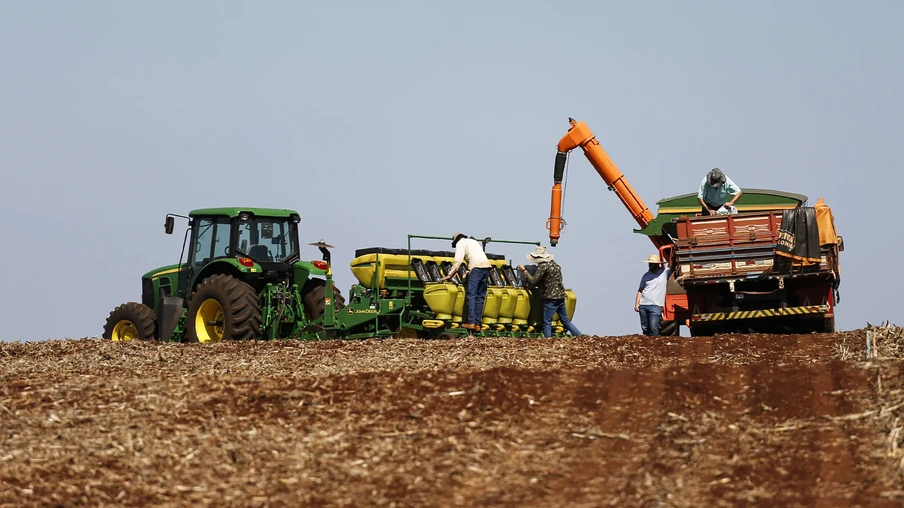Foto de máquinas e trabalhadores em lavoura preparando a semeadura da soja. Foto de máquinas e trabalhadores em lavoura preparando a semeadura da soja.
