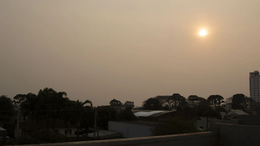 Foto de céu acizentado com sol avermelhado sobre cidade. Foto de céu acizentado com sol avermelhado sobre cidade.