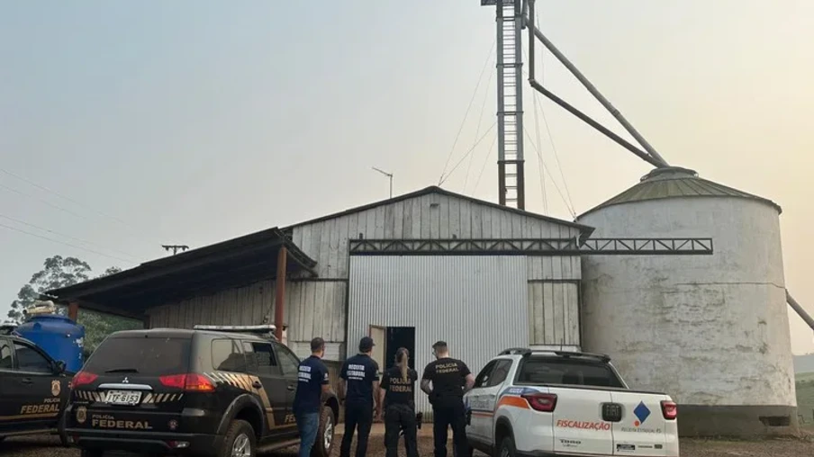 Foto de duas viaturas e quatro agentes em frente a silo. Foto de duas viaturas e quatro agentes em frente a silo.