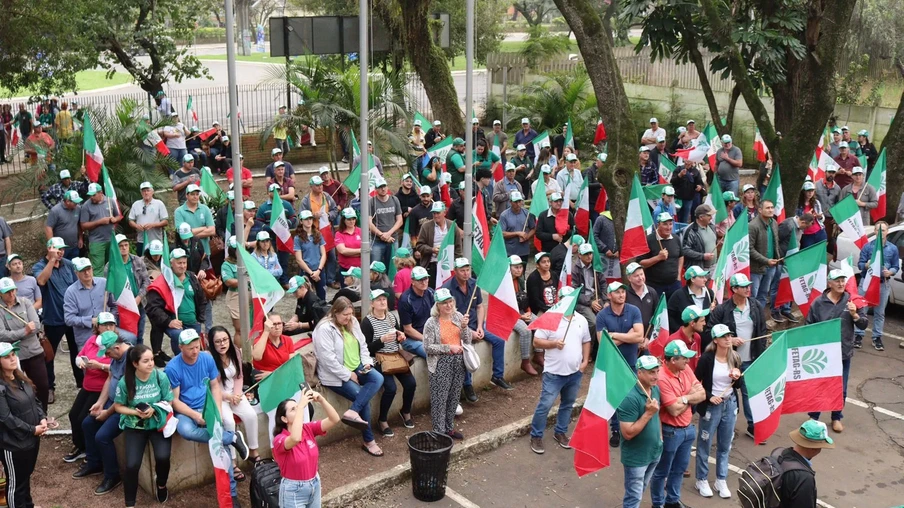 Foto de pessoas reunidas segurando bandeiras da Fetag-RS. Foto de pessoas reunidas segurando bandeiras da Fetag-RS.