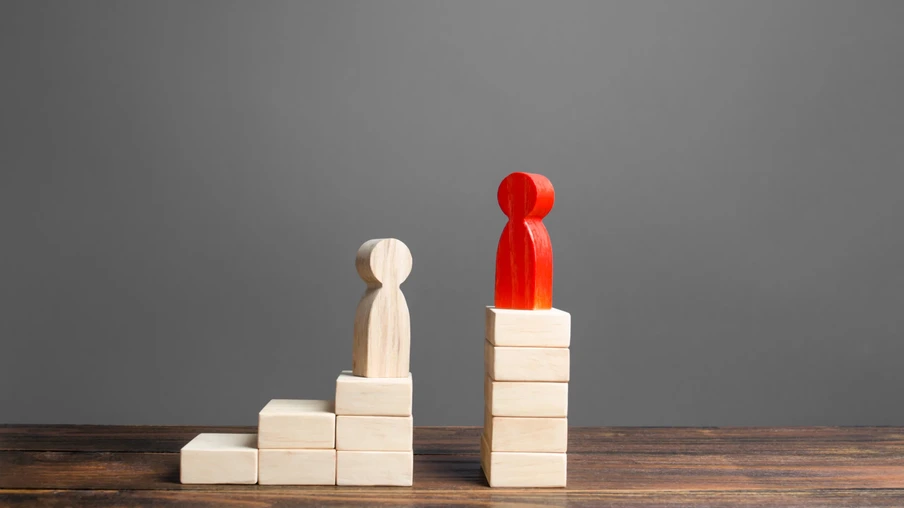 Imagem com um boneco vermelho sobre uma pilha de blocos mais alto que um boneco branco sobre uma pilha de blocos menor. Imagem com um boneco vermelho sobre uma pilha de blocos mais alto que um boneco branco sobre uma pilha de blocos menor.