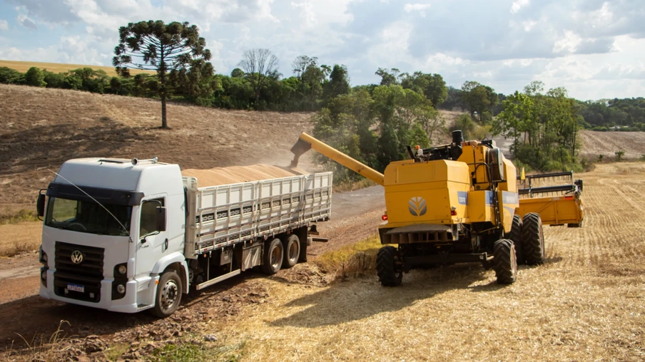 Foto de colheitadeira amarela despejando grãos de trigo em carreta. Foto de colheitadeira amarela despejando grãos de trigo em carreta.
