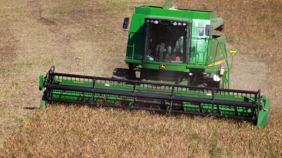 Foto de colheitadeira verde avançando em lavoura de feijão. Foto de colheitadeira verde avançando em lavoura de feijão.