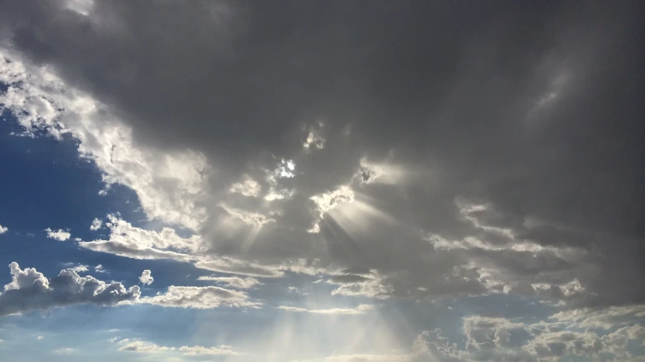 Foto de céu com nuvens escuras e raios de sol. Foto de céu com nuvens escuras e raios de sol.