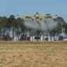 Foto de avião agrícola sobrevoando e realizando a pulverização.